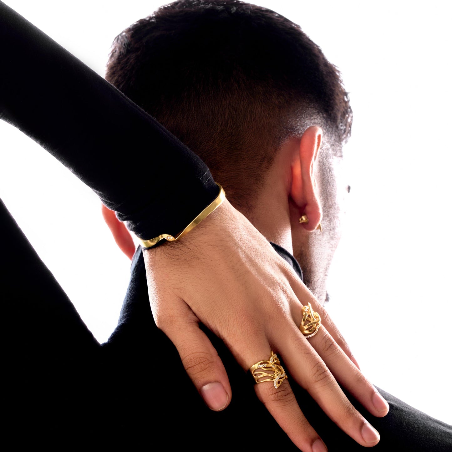 Person wearing gold rings on a white background