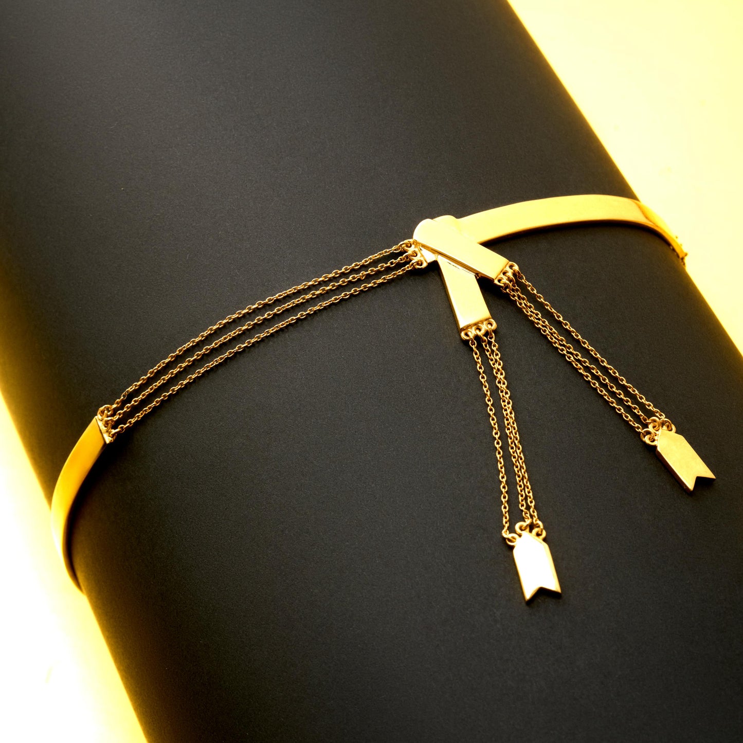 Gold bracelet with hanging charms on a black surface