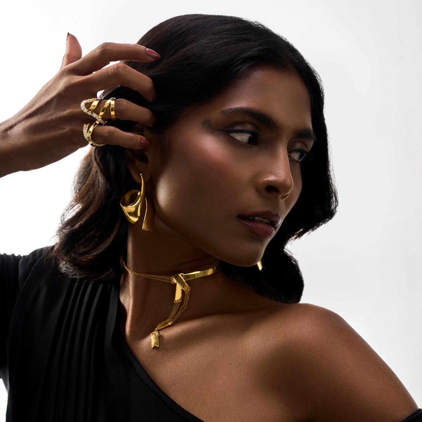 Woman wearing gold jewelry against a white background