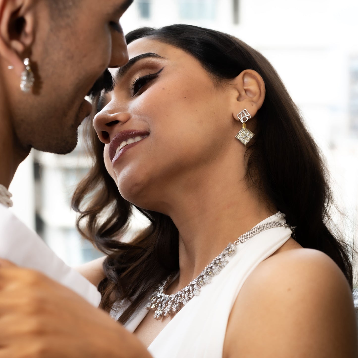 Woman wearing diamond earrings and a necklace, close-up of face with blurred background