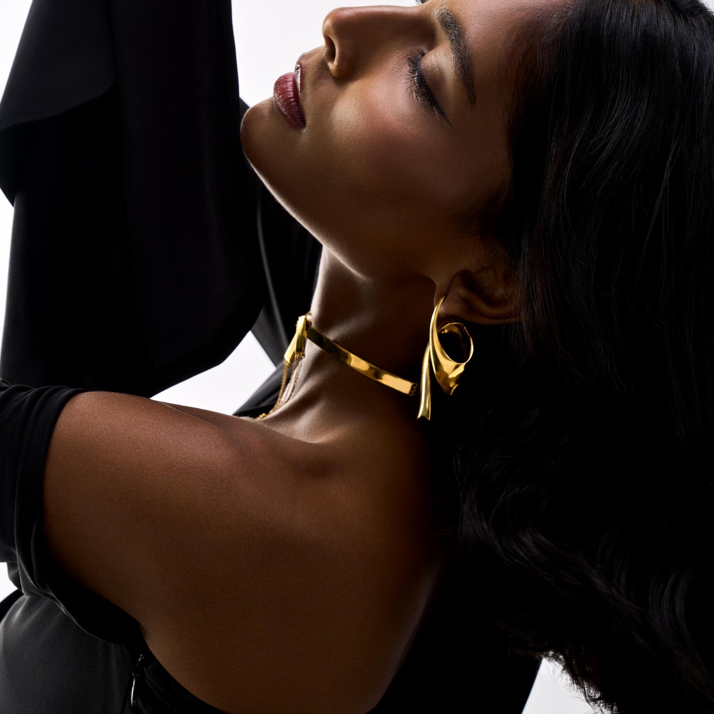 Woman wearing a gold necklace against a white background