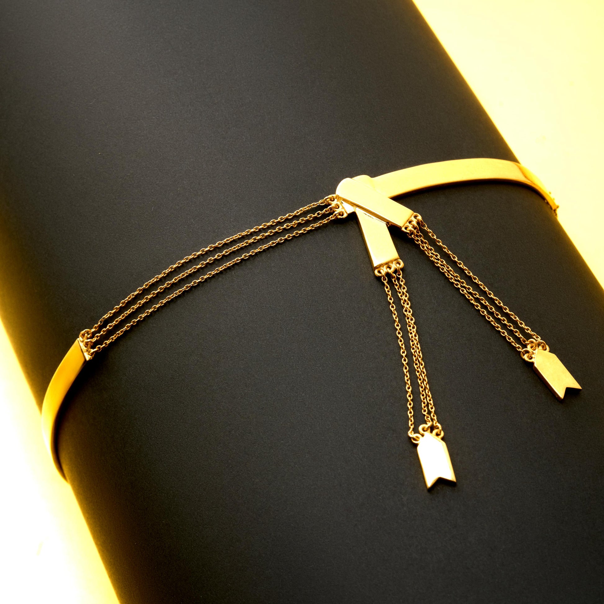 Gold bracelet with hanging charms on a black surface