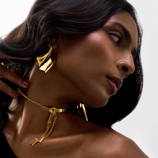Woman wearing gold jewelry with a neutral background