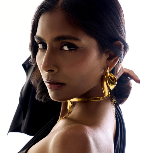 Woman wearing gold earrings and a necklace with a white background